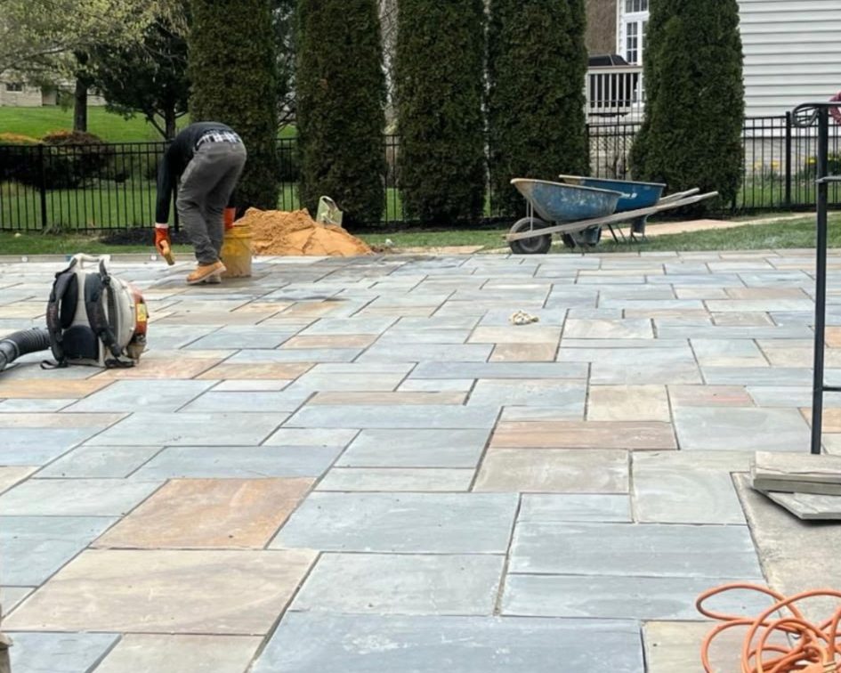 Crew member finishing the joints on a large cut bluestone patio
