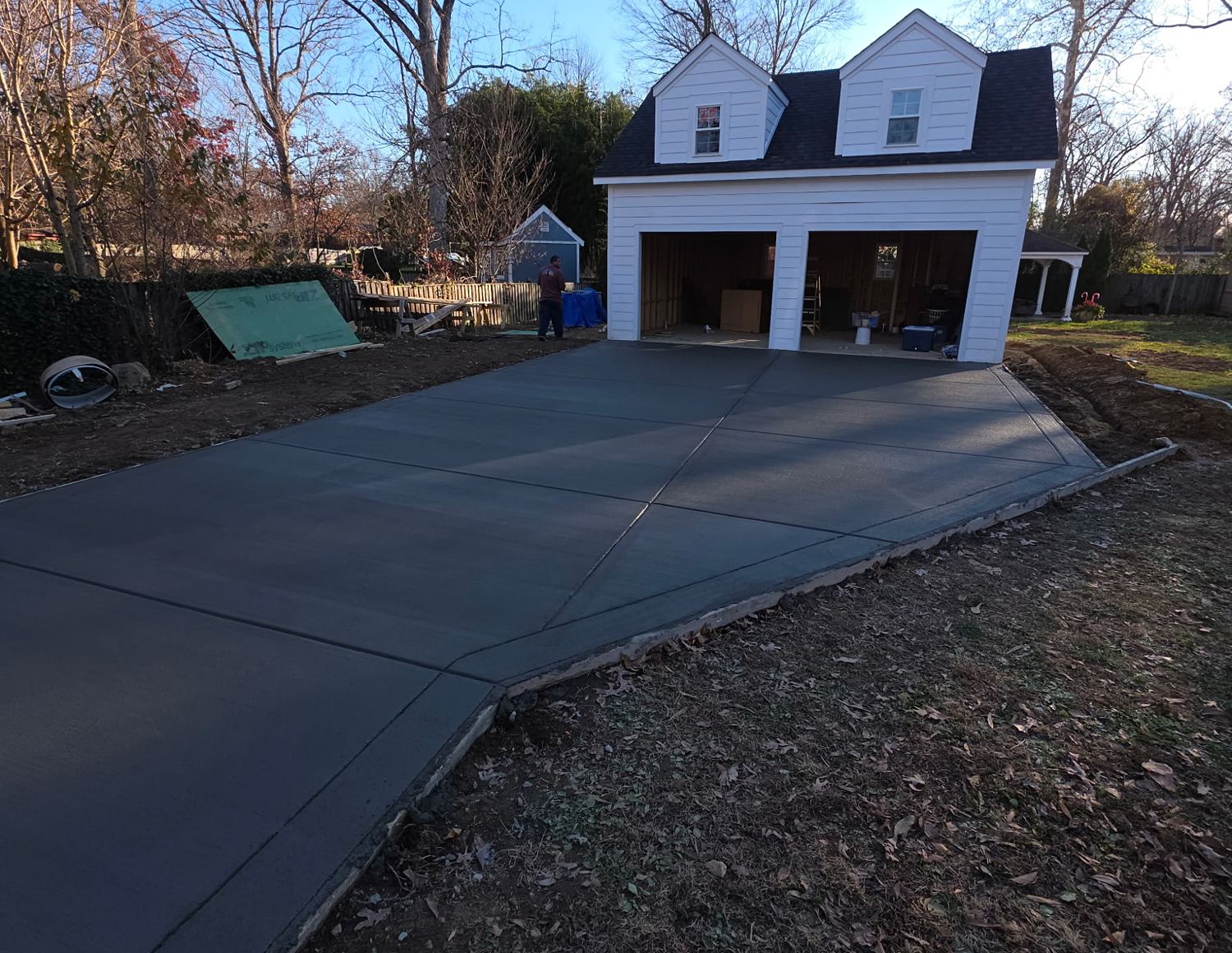 New broom-finished concrete driveway leading to a detached two-car garage