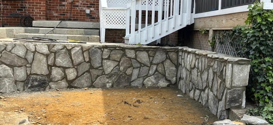 Mortared natural stone retaining wall turning a corner below bluestone steps