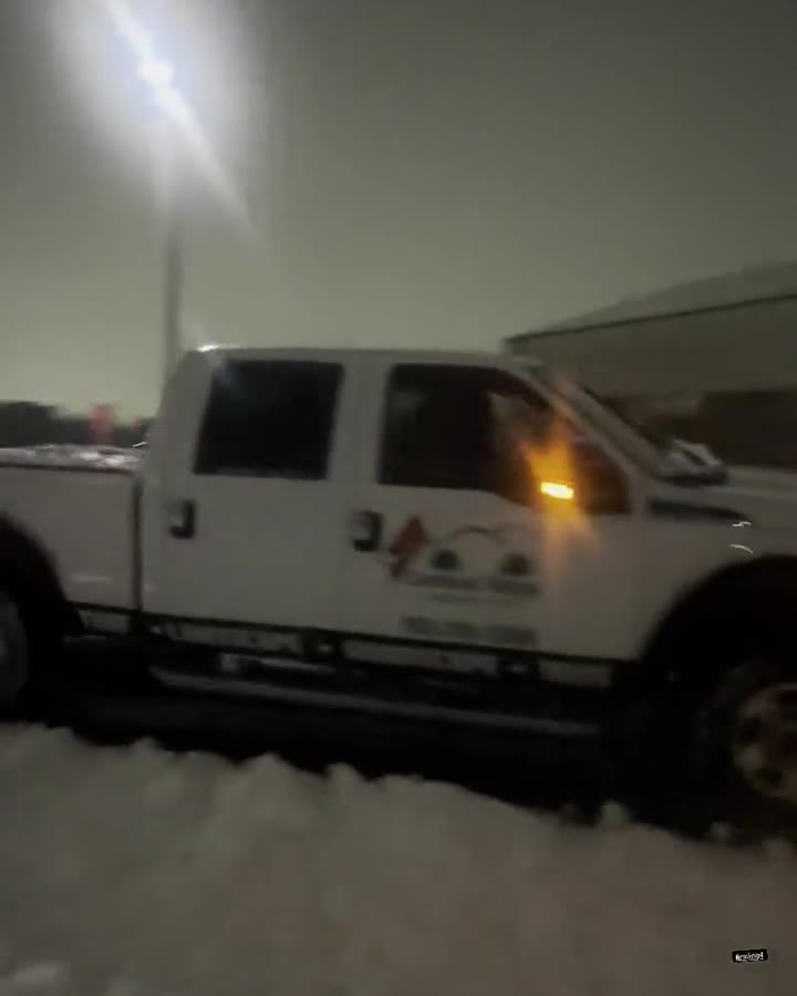 Cardinal Ridge plow truck clearing a snow-covered commercial lot at night
